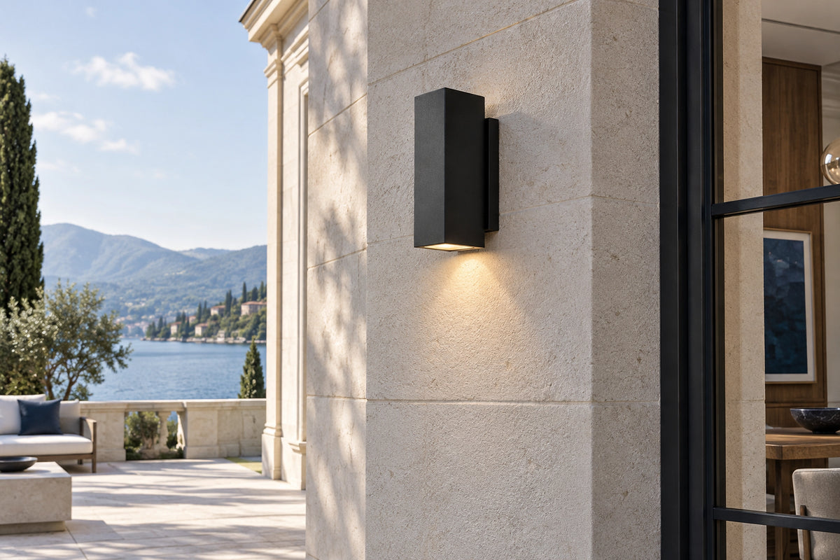 Luminaire extérieur noir sur une façade en pierre claire, sous une lumière naturelle