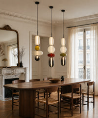 Trois suspensions en verre allumées au-dessus d’une table à manger nette