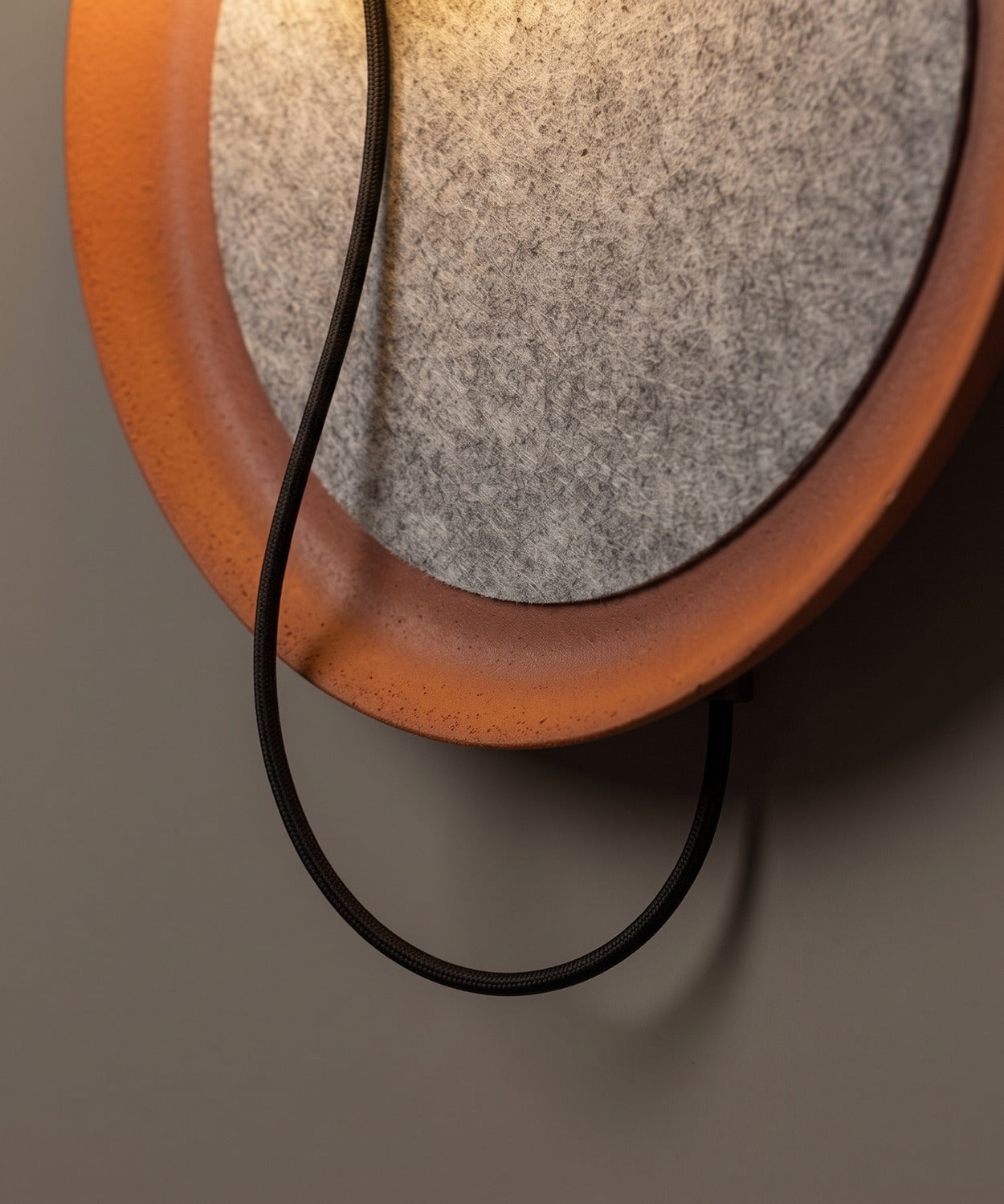 Boucle du câble noir sous le disque de l'applique murale
