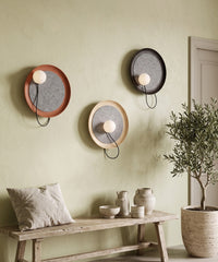 Trois appliques aux finitions noire, terracotta et crème sur le mur d'un séjour bohème