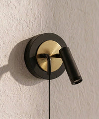 Gros plan sur la rosace noire et dorée et le spot orientable de l’applique de chevet