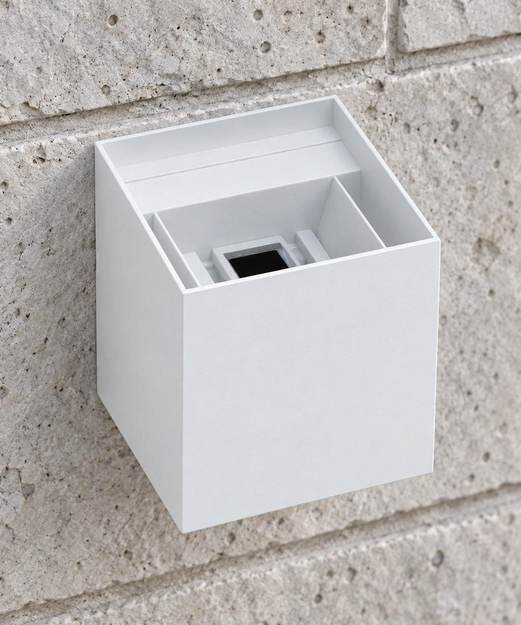 Vue rapprochée par le dessus du boîtier blanc d’une applique cube sur un mur en pierre