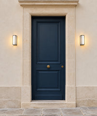 Deux lanternes murales noires éclairent les côtés d’une porte d’entrée bleue
