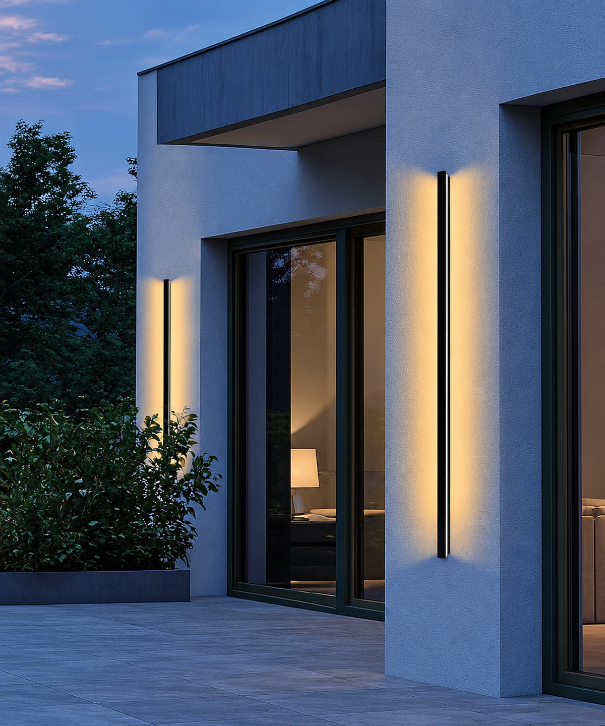 Deux appliques longues noires éclairent une façade et une terrasse au crépuscule Image