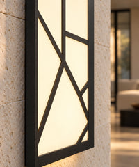 Détail du motif noir devant le panneau lumineux, applique installée sur un mur en pierre