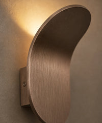 Gros plan sur la courbe de la feuille d’aluminium brossé bronze et sa vis de fixation