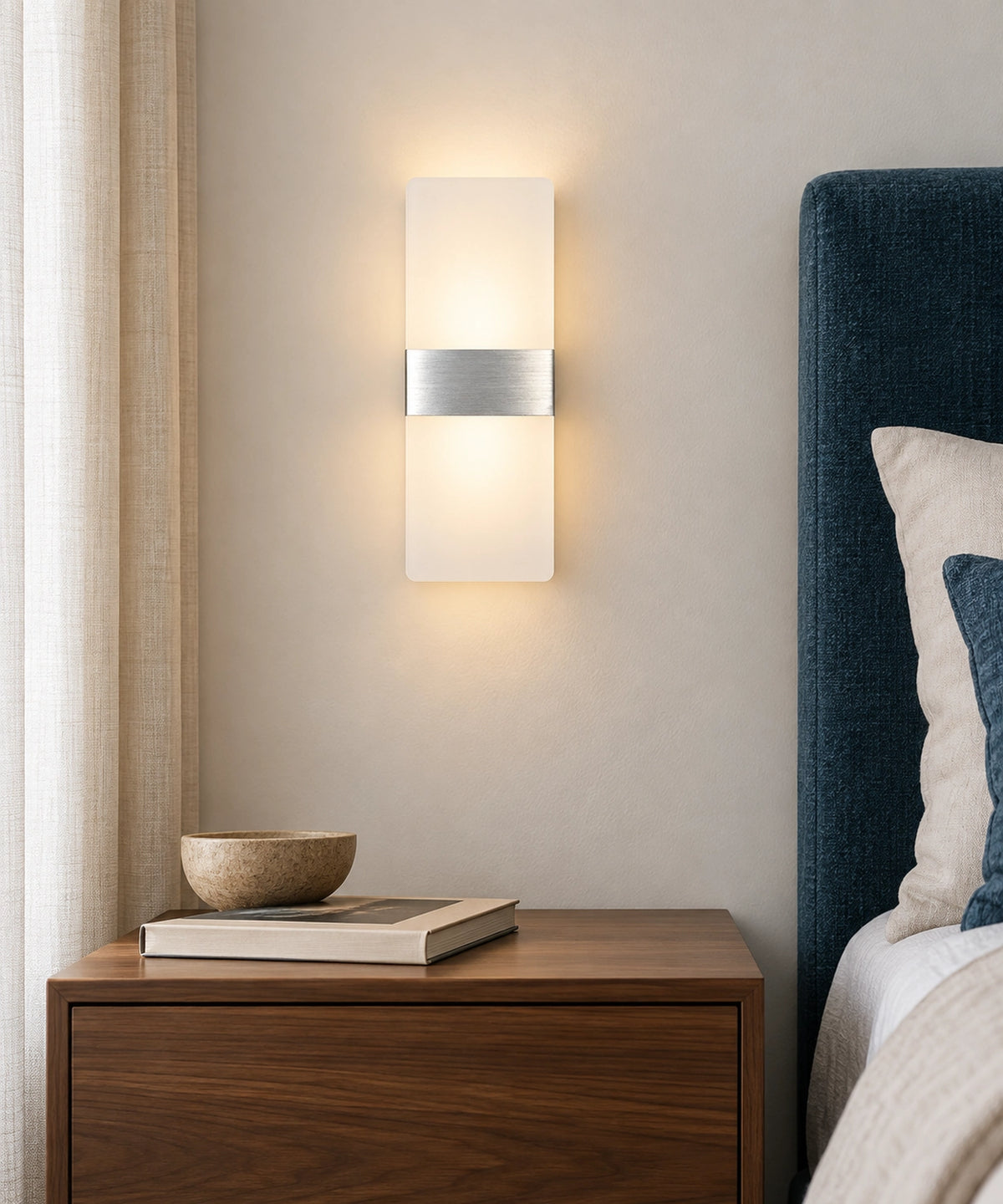 Applique argentée à lumière diffuse au-dessus d’une table de chevet