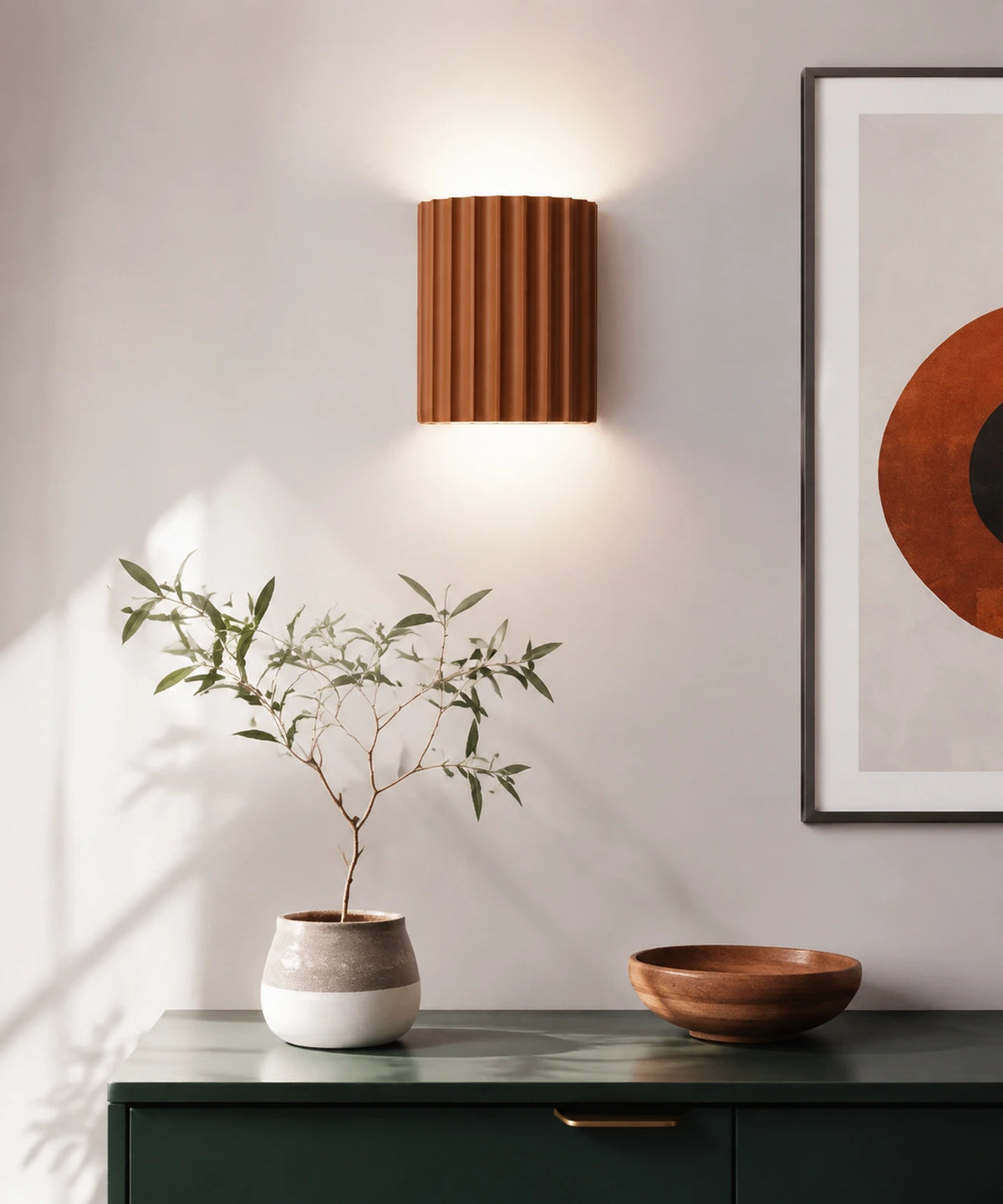 Applique murale cannelée orange allumée au-dessus d’un meuble vert