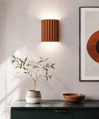 Applique murale cannelée orange allumée au-dessus d’un meuble vert