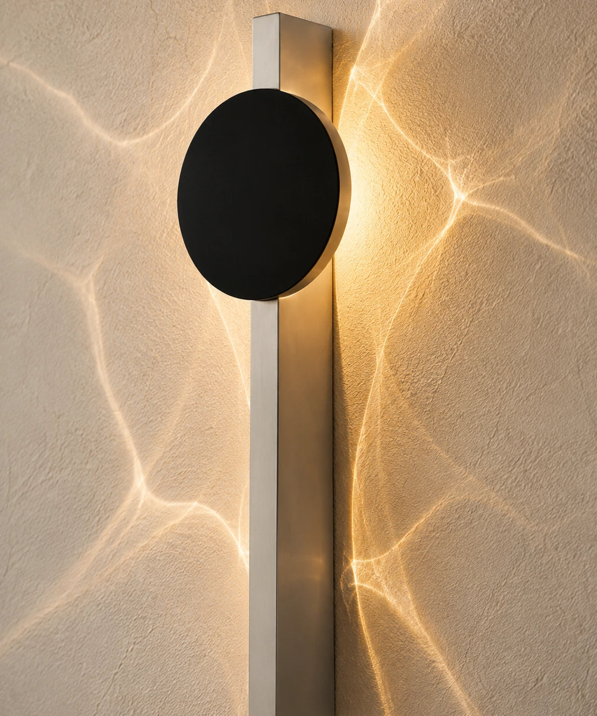Gros plan sur les ondulations de lumière projetées autour du disque noir de l’applique