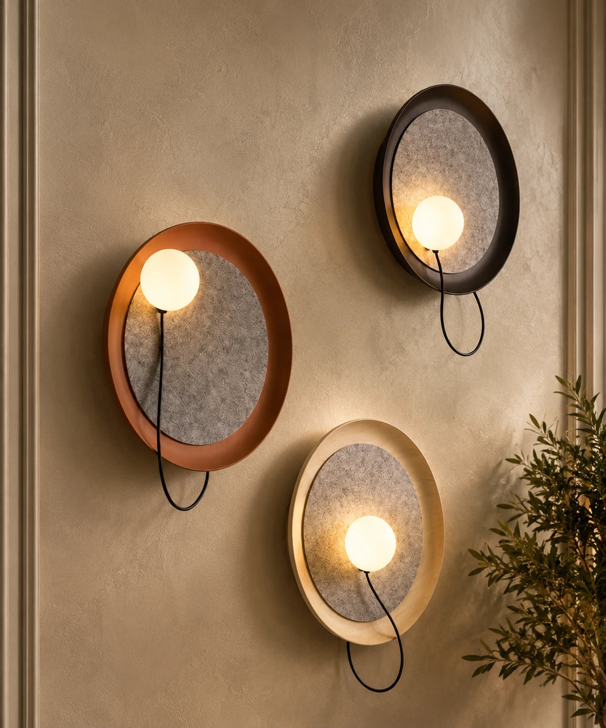 Applique murale en feutre, trois disques terracotta, noir et blanc allumés sur un mur enduit