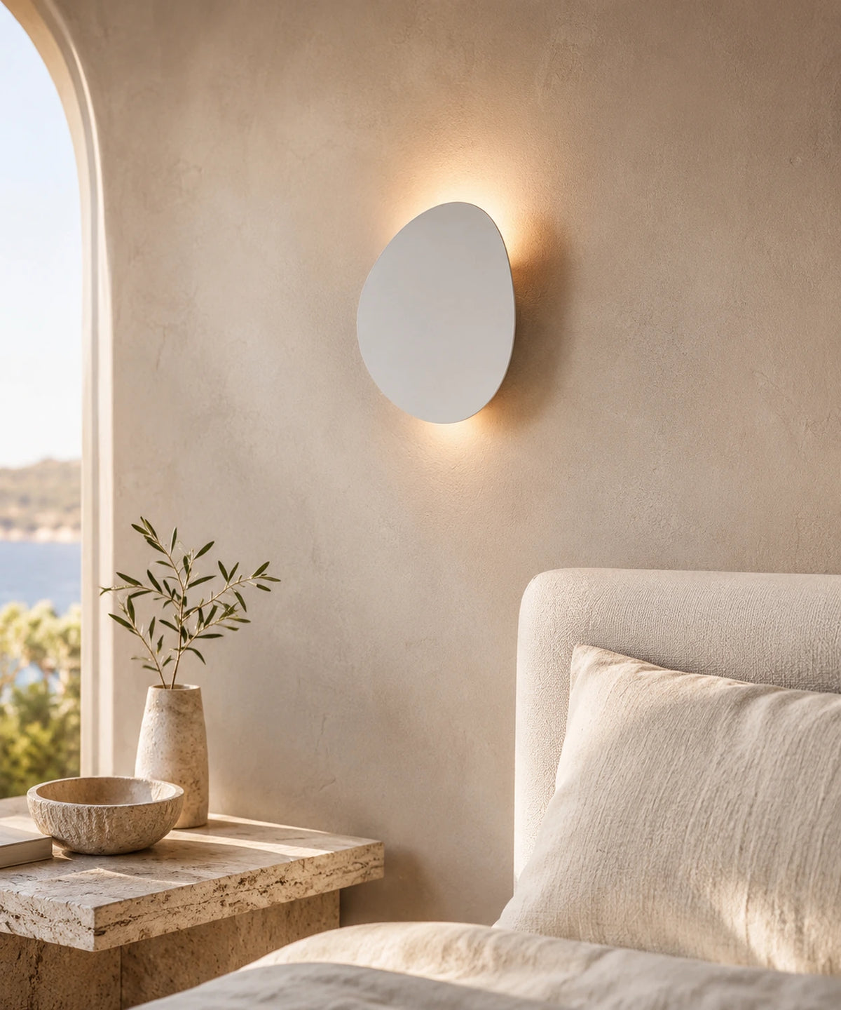 Applique murale galet blanc sable allumée en tête de lit, dans une chambre claire Image