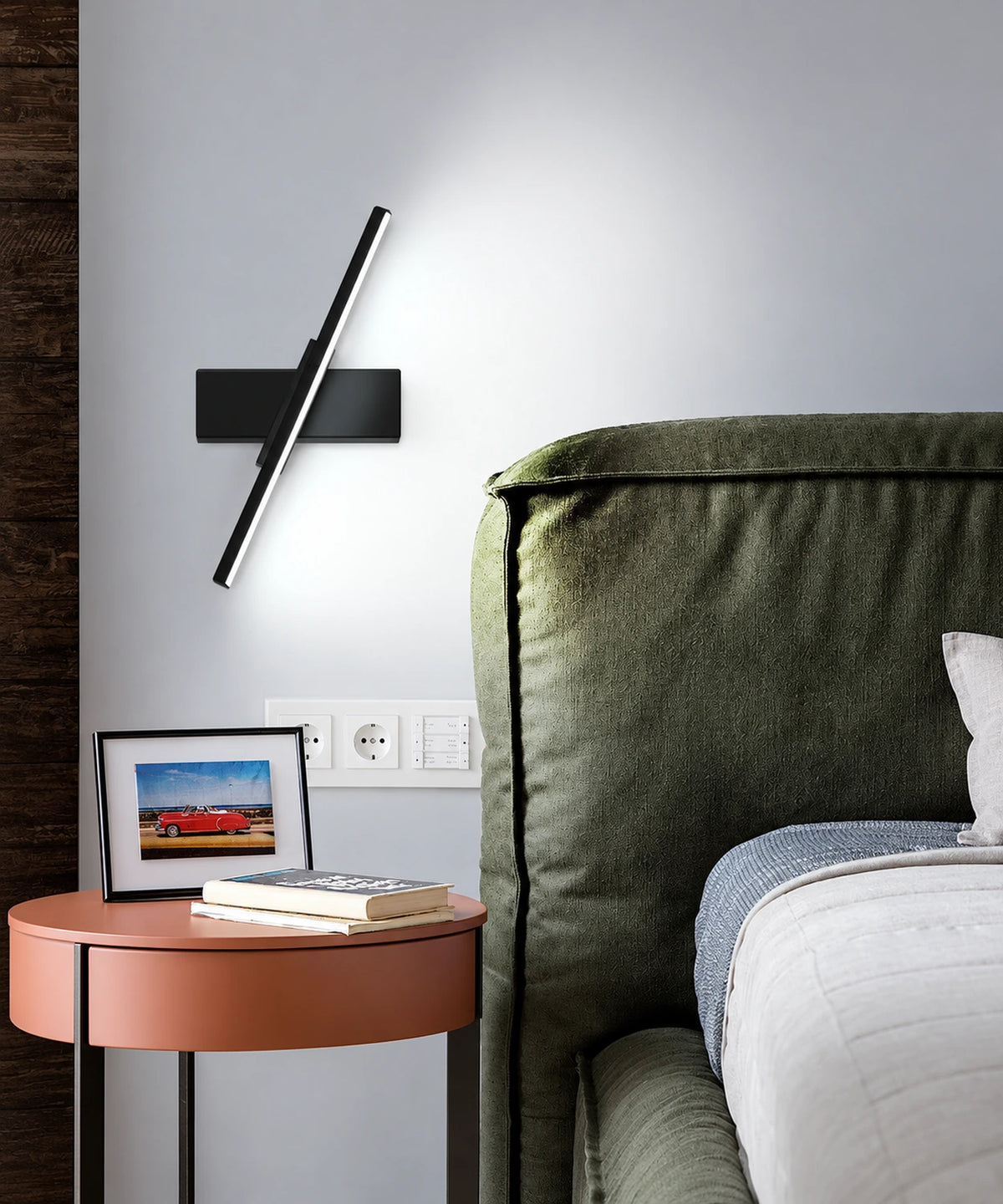 Applique murale LED orientable noire près d’un lit vert, barre inclinée et diffuseur linéaire allumé