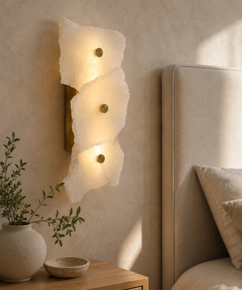 Applique murale marbre blanc à trois plaques allumée au chevet, tête de lit beige et vase