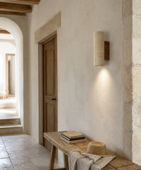 Applique murale en pierre naturelle, allumée dans un couloir de maison ancienne