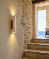 Applique murale en travertin et bois, allumée le long d'une montée d'escalier en pierre