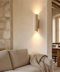 Applique murale en travertin et bois, finition bois clair, allumée dans un salon