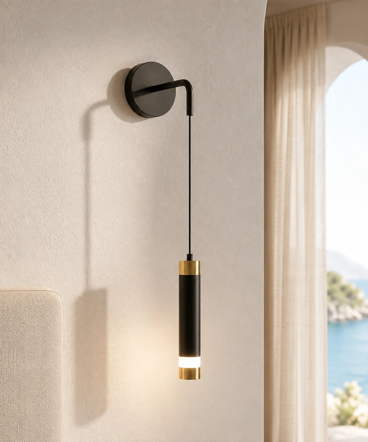 Applique murale tube suspendu noir et or allumée sur un mur enduit, fenêtre sur la mer