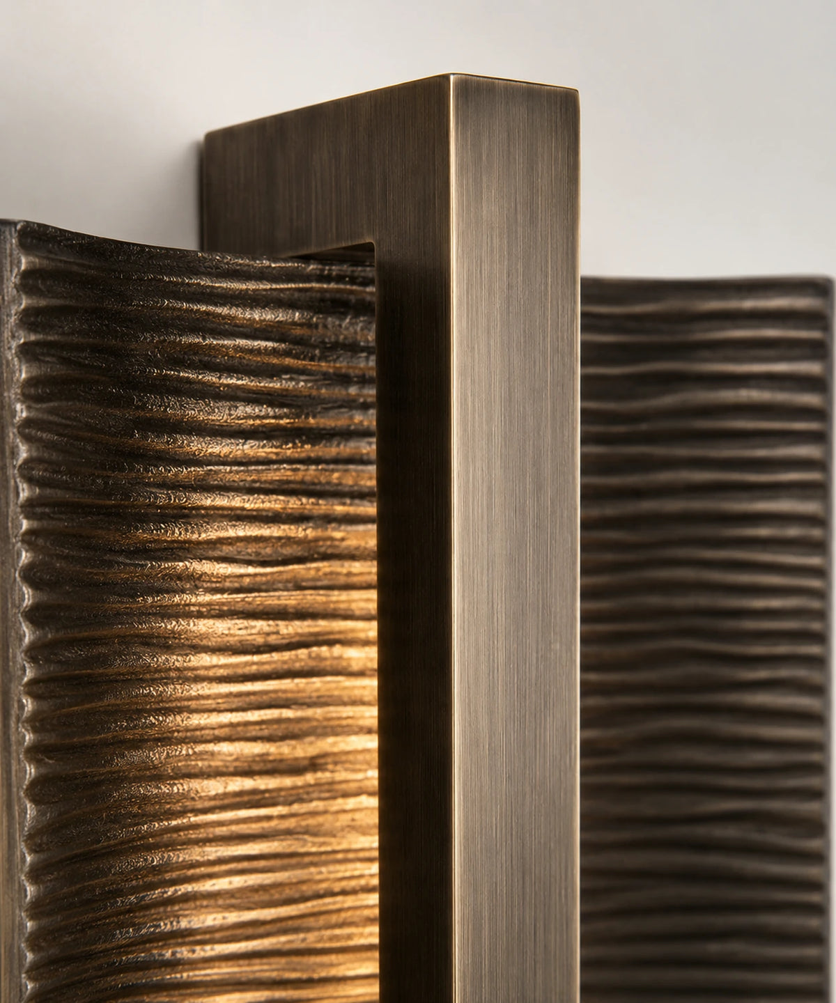 Détail de la barre en aluminium brossé et des nervures bronze de l’applique murale verticale