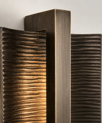Détail de la barre en aluminium brossé et des nervures bronze de l’applique murale verticale