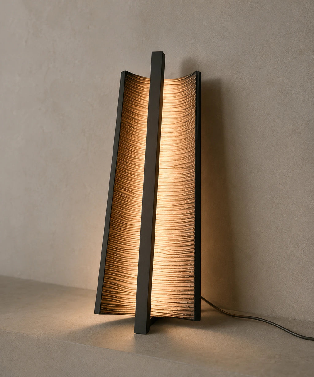Applique verticale en bronze nervuré posée debout, lumière rasante à travers les nervures