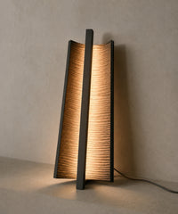 Applique verticale en bronze nervuré posée debout, lumière rasante à travers les nervures
