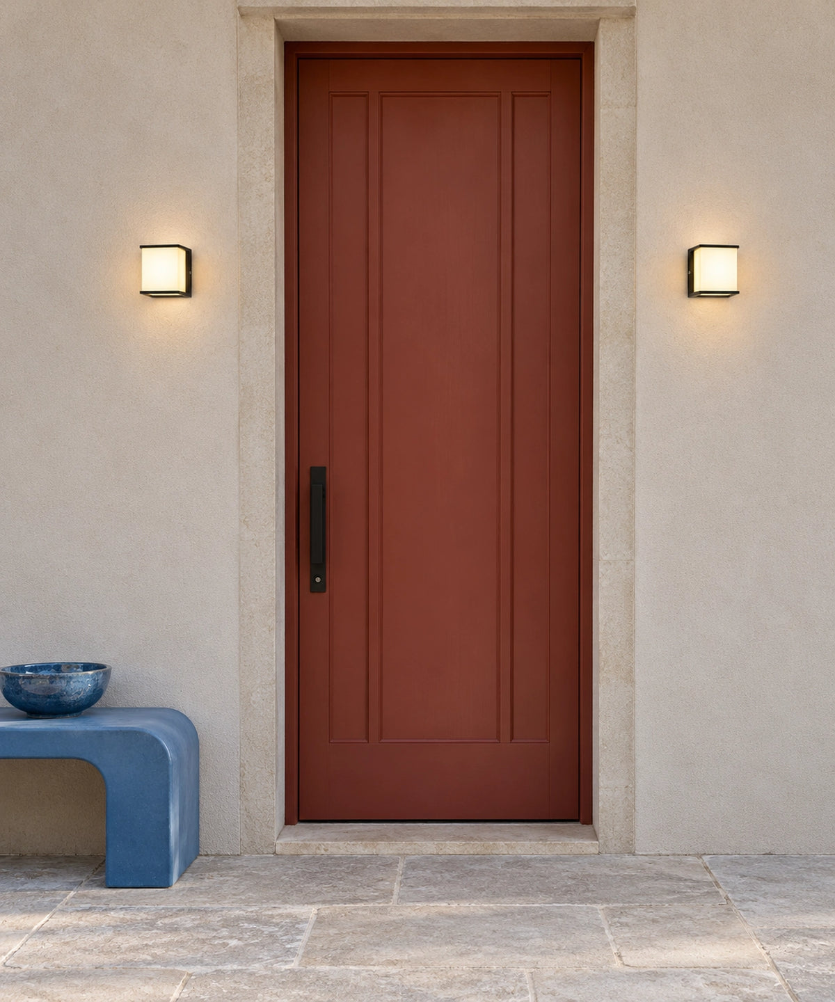 Deux appliques carrées noires encadrent une porte d’entrée rouge Image