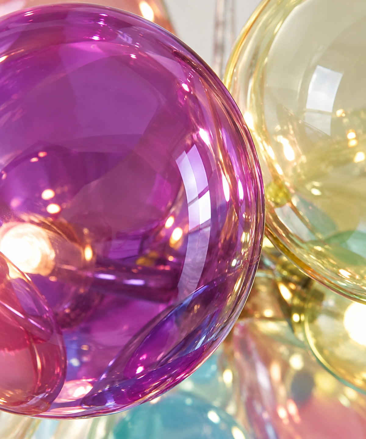 Détail des reflets dans les bulles en verre transparent violet et jaune de la suspension Zéphyr