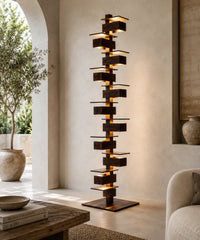 Grand lampadaire design à plateaux empilés, finition noyer, allumé dans un salon ouvert sur le jardin