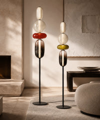 Deux lampadaires boules de verre, accords rouge et olive, allumés dans un salon en travertin