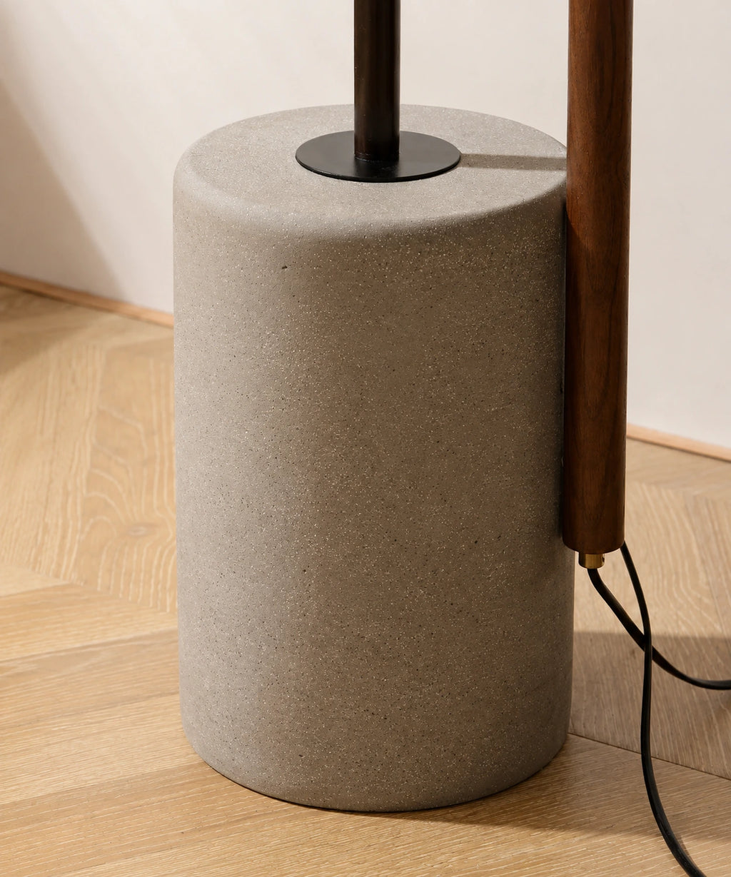Socle cylindrique en ciment coulé du lampadaire liseuse, câble noir et mât en bois