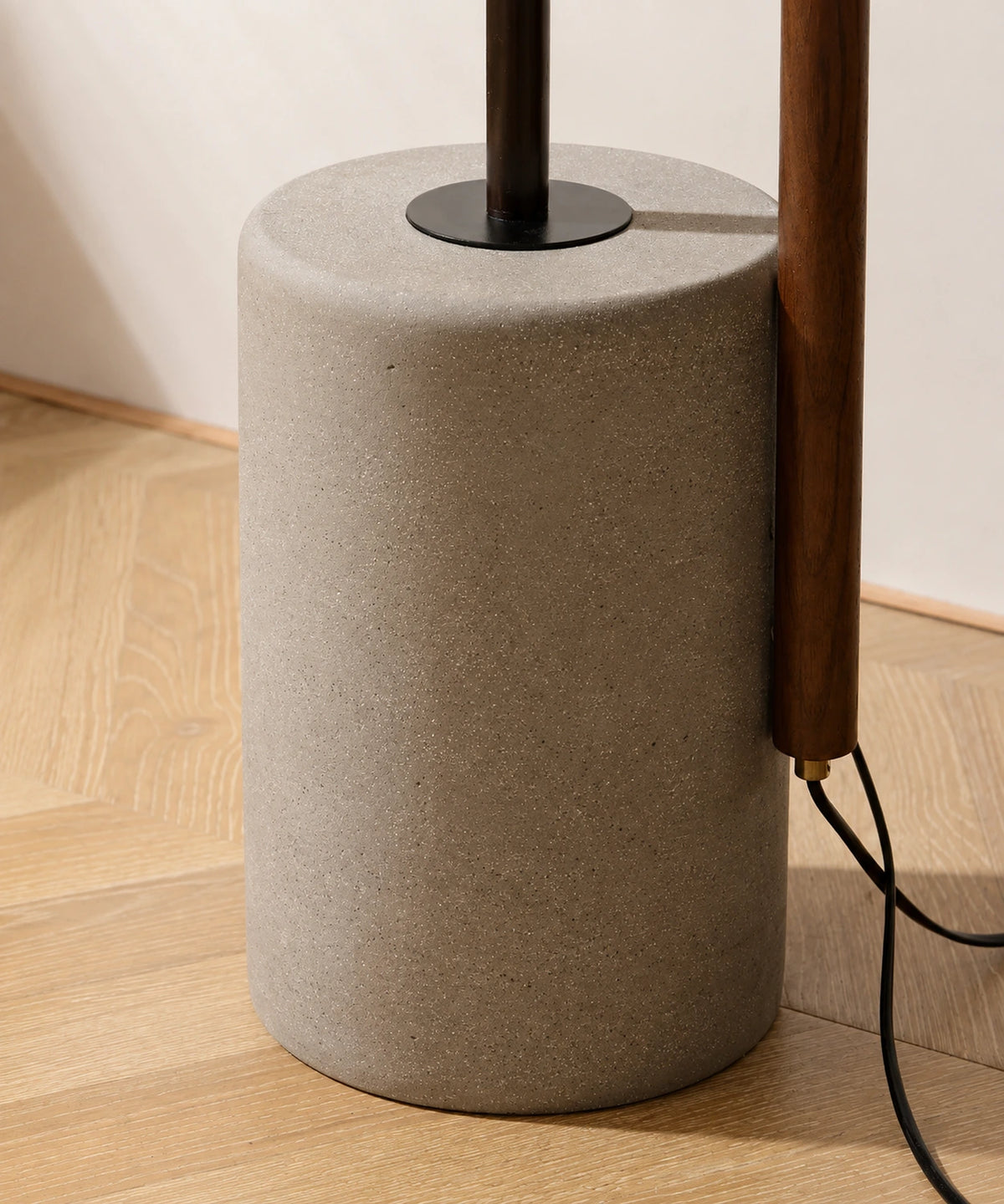 Socle cylindrique en ciment coulé du lampadaire liseuse, câble noir et mât en bois