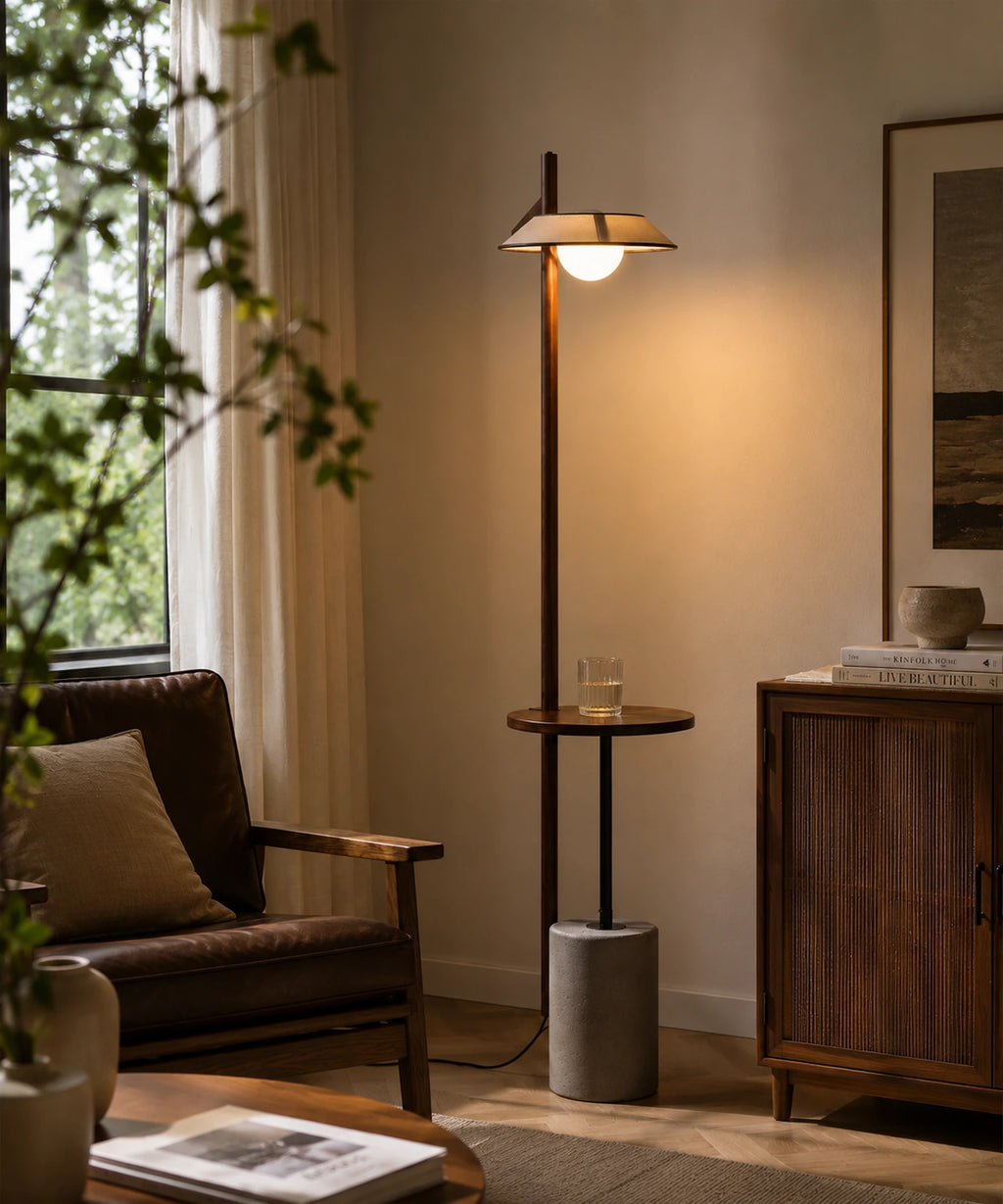 Lampadaire liseuse en bois et ciment allumé près d’un fauteuil de lecture et d’une fenêtre