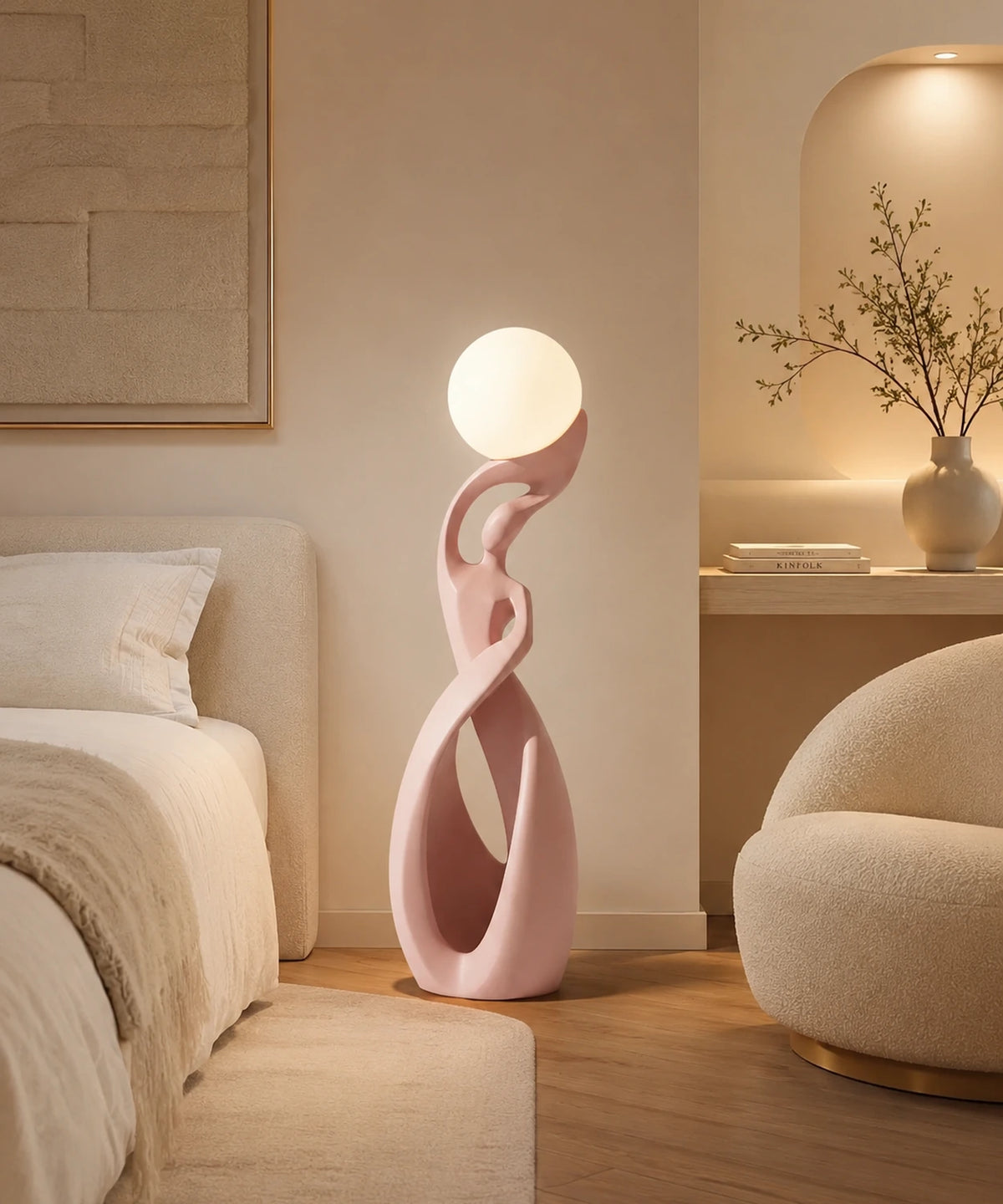 Lampadaire sculpture rose poudré allumé entre un lit et un fauteuil en bouclette