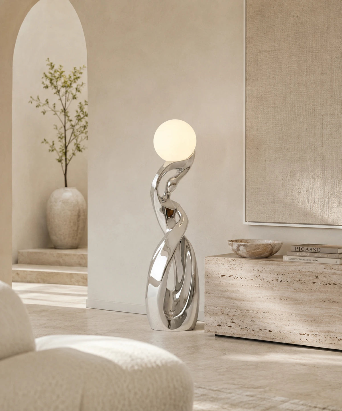 Lampadaire sculpture chrome argent allumé sous une arche, banc en travertin