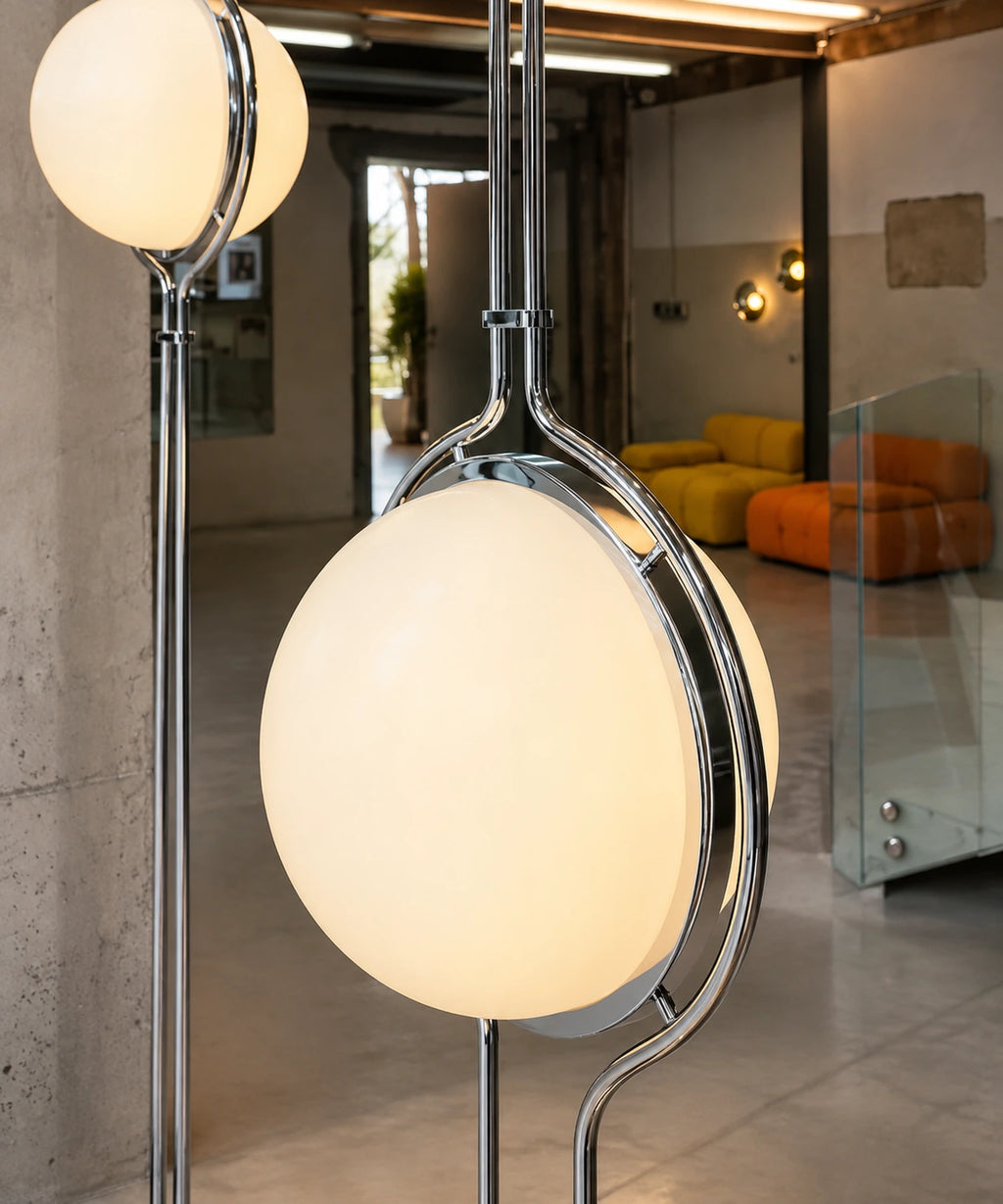 Gros plan sur l’anneau chromé et la boule opaline allumée du lampadaire sol-plafond