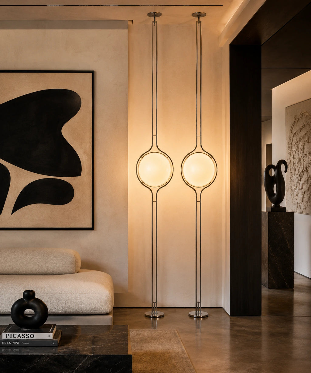 Deux lampadaires sol-plafond à boule opaline allumés dans un salon aux murs enduits