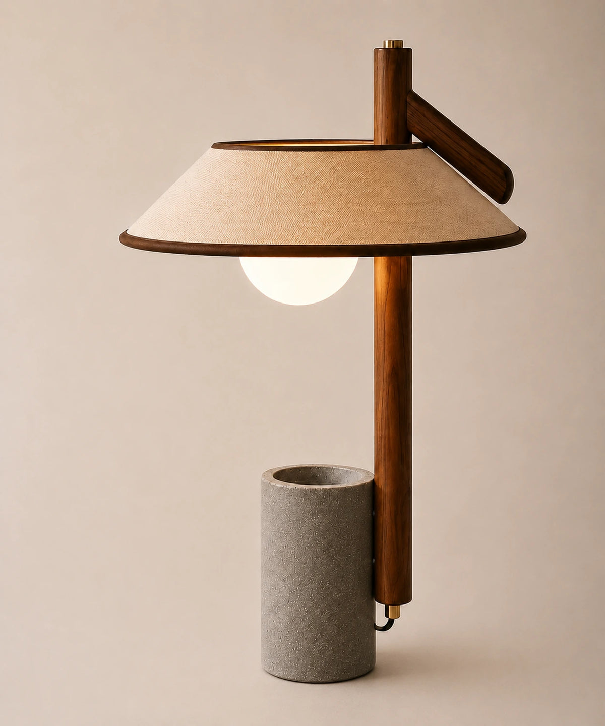 Lampe à poser béton, mât en noyer, abat-jour en lin et globe opalin, vue d’ensemble sur fond beige