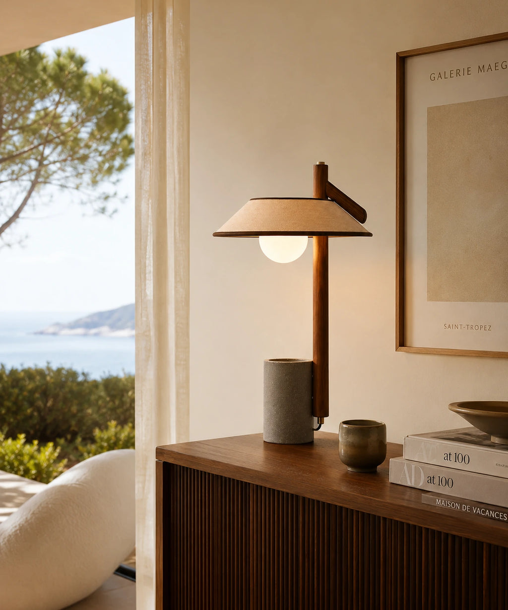 Lampe à poser béton à globe opalin posée devant une baie ouverte sur la Méditerranée