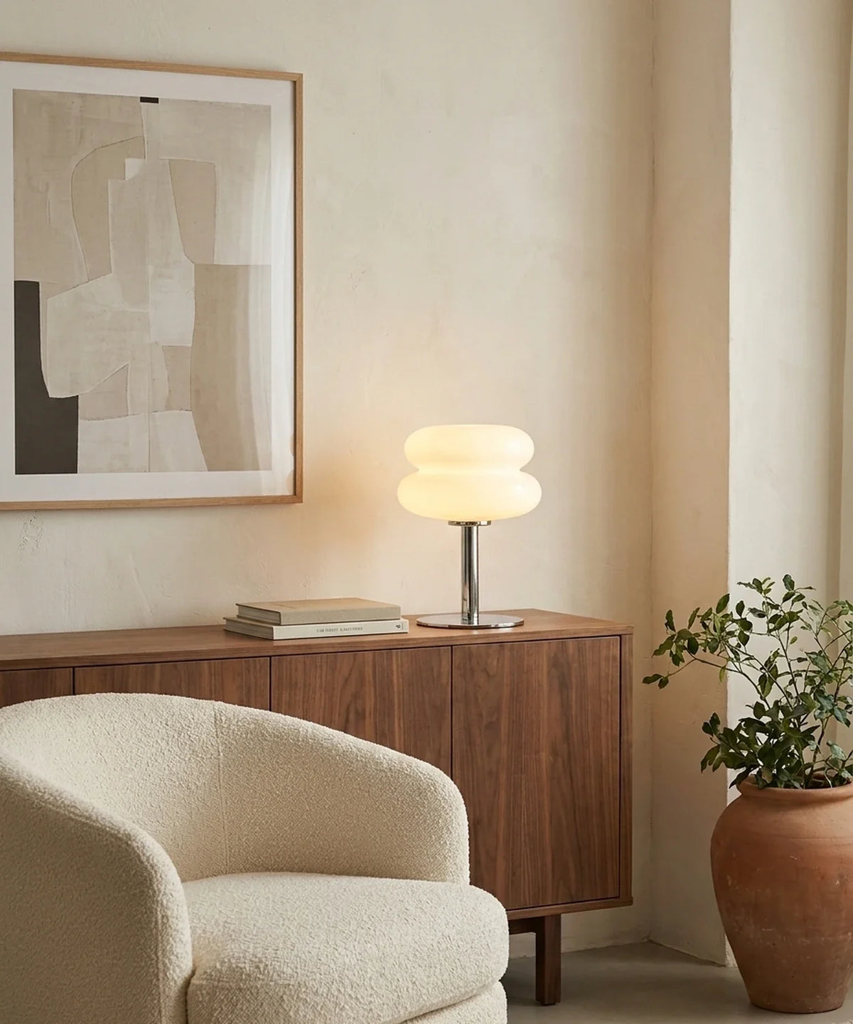 Lampe à poser verre soufflé de 28 cm sur un buffet en noyer, à côté d un fauteuil en bouclette