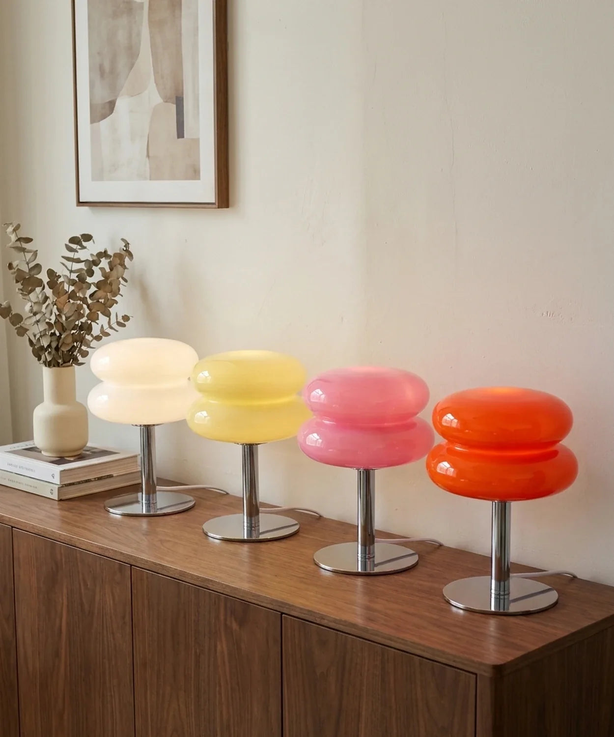 Quatre lampes à poser verre soufflé alignées sur un buffet en noyer : blanc, jaune, rose et orange, allumées Image