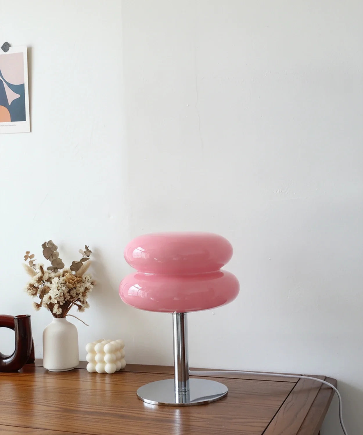 Lampe à poser verre soufflé rose bonbon sur pied disque chromé, posée sur un buffet en noyer