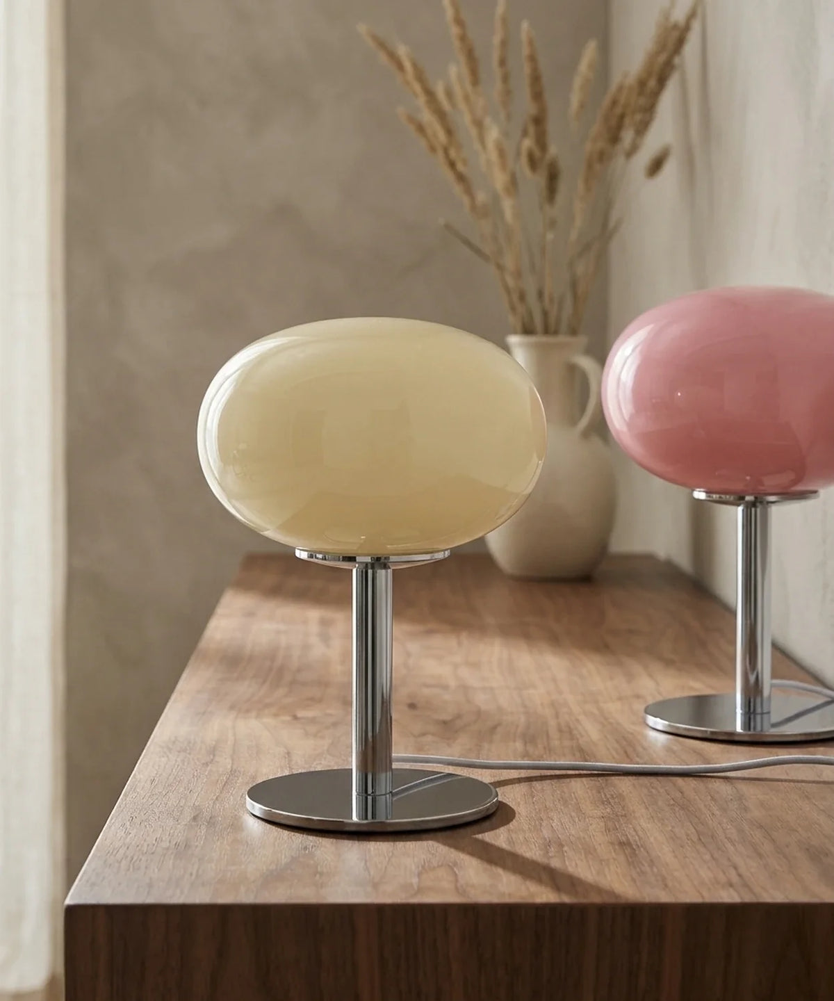 Deux lampes de chevet USB en verre soufflé, crème et rose poudré, sur un buffet en noyer