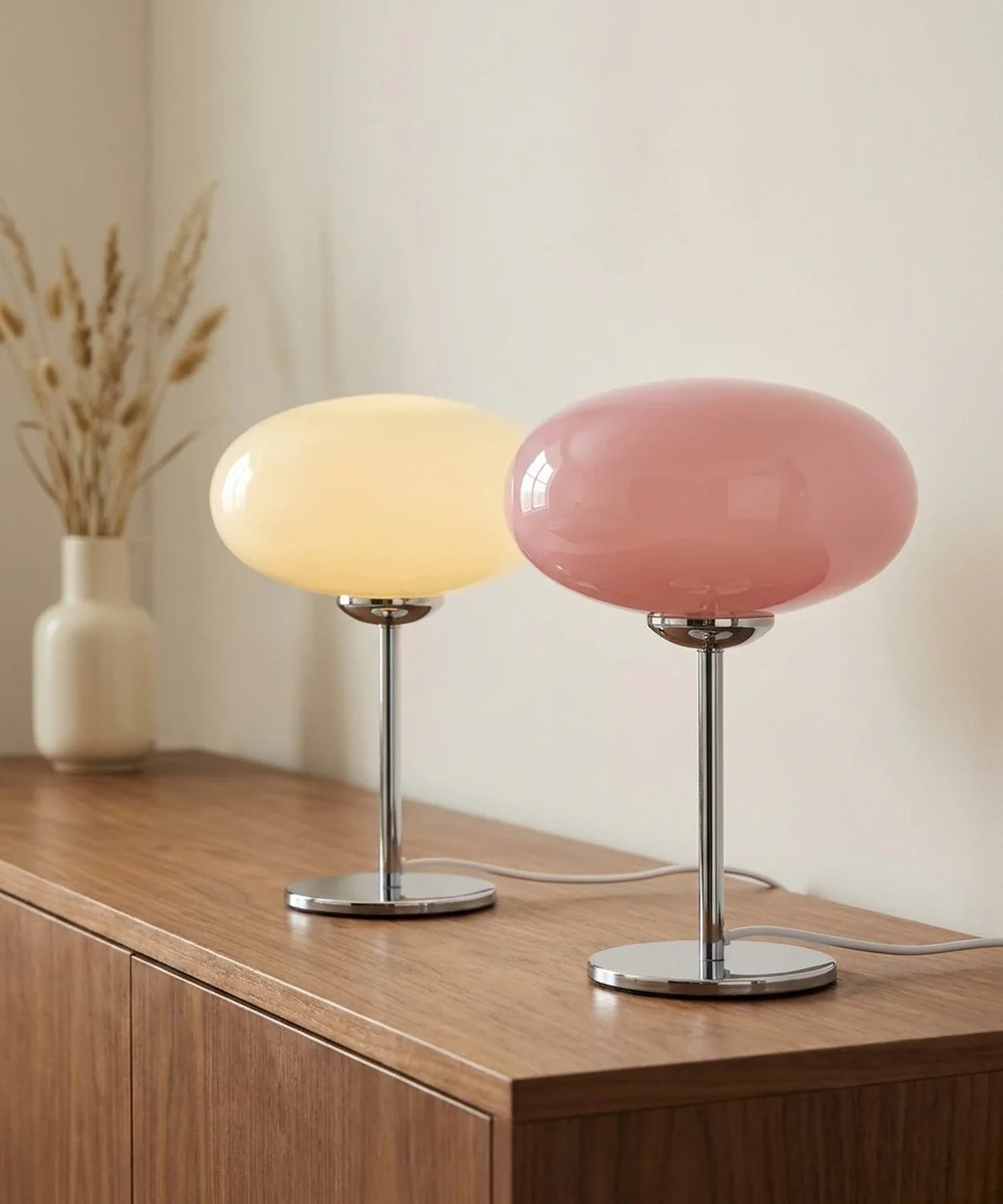 Les deux coloris de la lampe de chevet en verre soufflé réunis sur une console en noyer Image