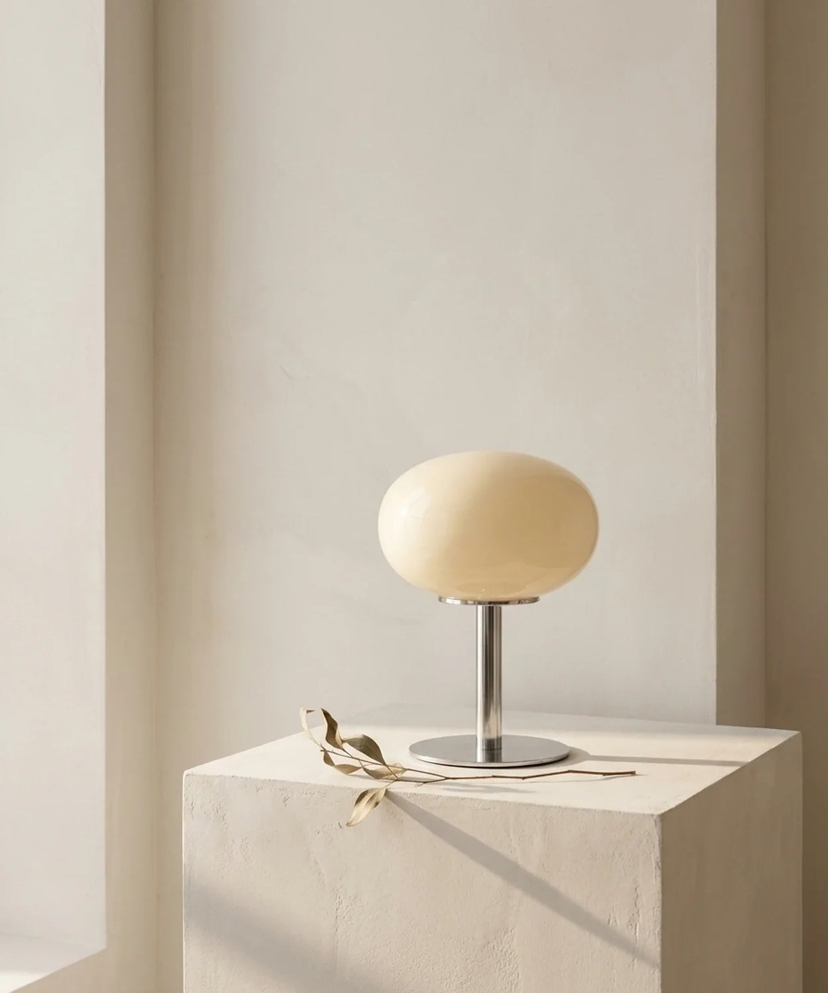 Lampe de chevet en verre soufflé crème posée sur un socle d enduit brut