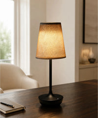 Lampe sans fil noire avec abat-jour conique en tissu sur une table sombre
