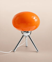Lampe de table rechargeable en verre orange brillant sur trépied chromé
