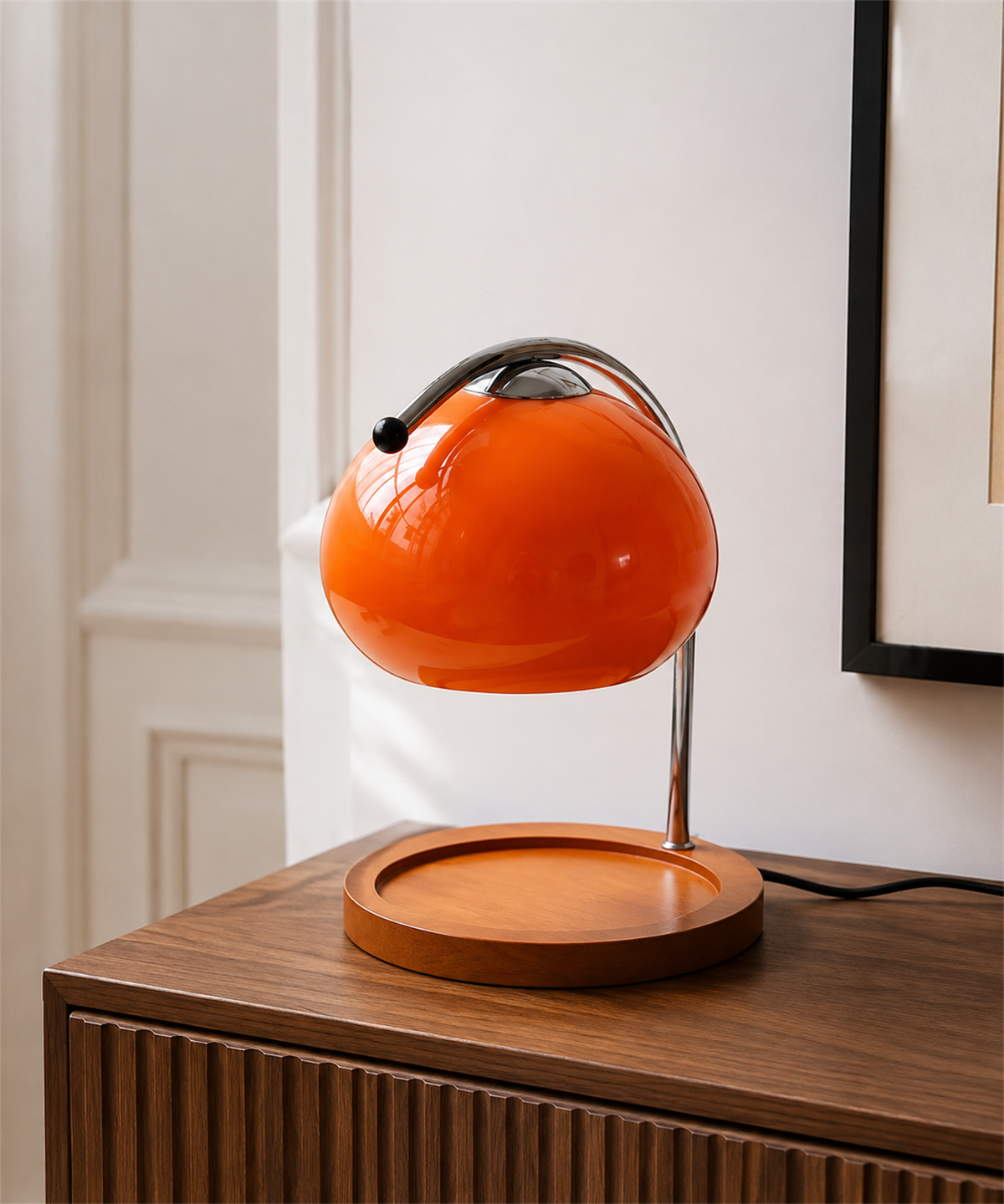 Lampe globe orange avec plateau vide, posée sur une console en bois devant un mur clair Image