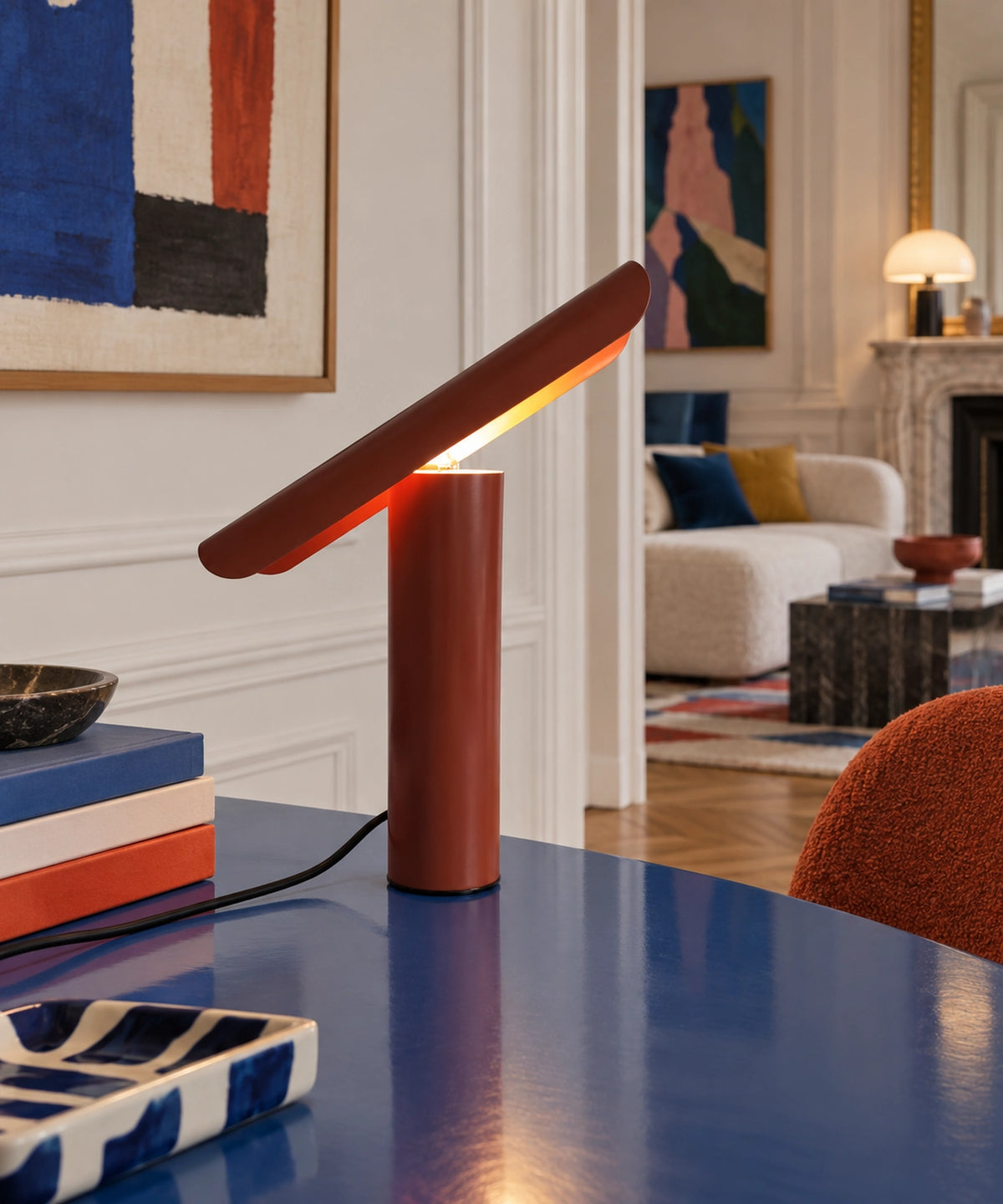 Lampe rouge cuivré à réflecteur demi-tube sur une console bleue