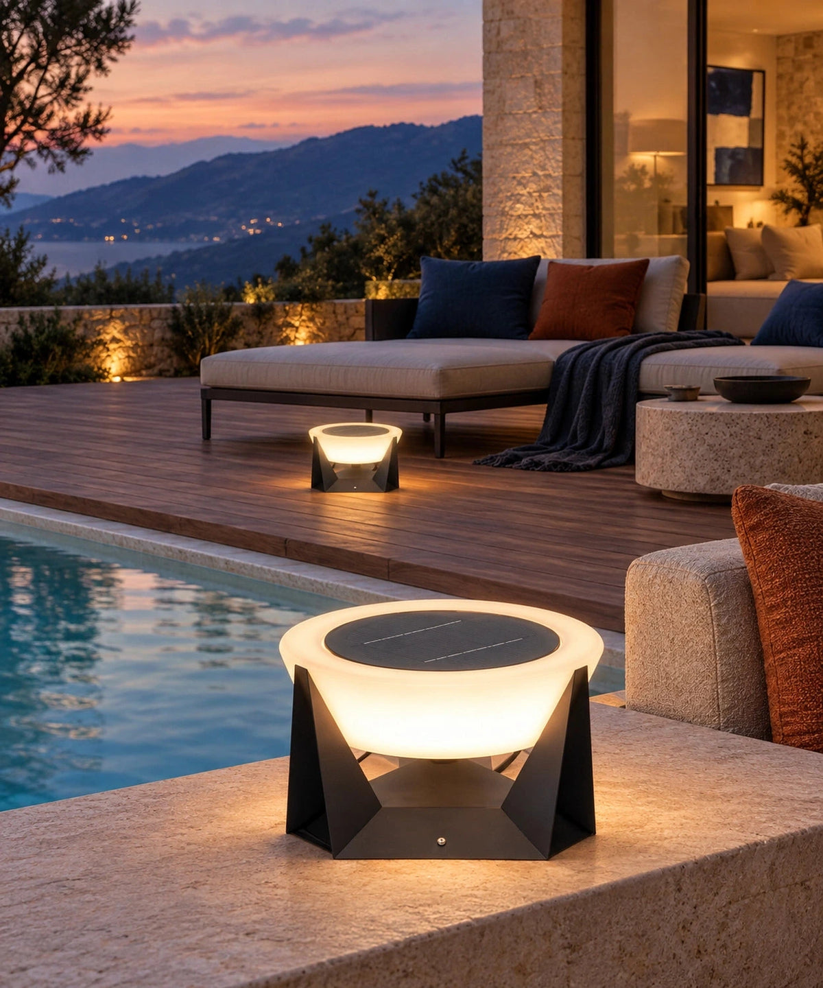 Lampe solaire à vasque ronde au premier plan d’une terrasse près d’une piscine